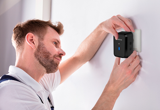 Mão plugando o módulo interno da campainha em uma tomada.