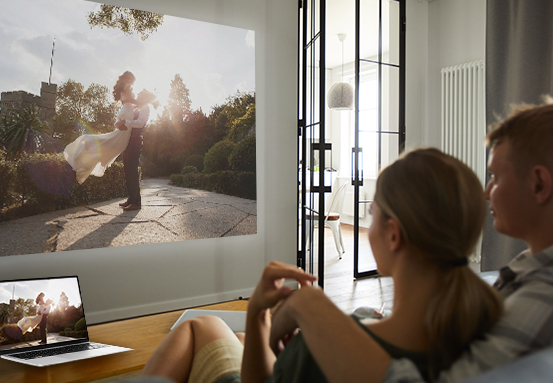 Celular espelhando sua tela em uma parede através do projetor